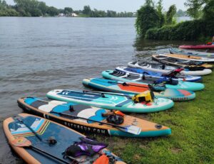Plusieurs paddleboards sur le bord de l'eau dans notre article Les meilleurs endroits pour faire du paddleboard au Québec #paddleboardquebec #supquebec #plancheapagaiequebec