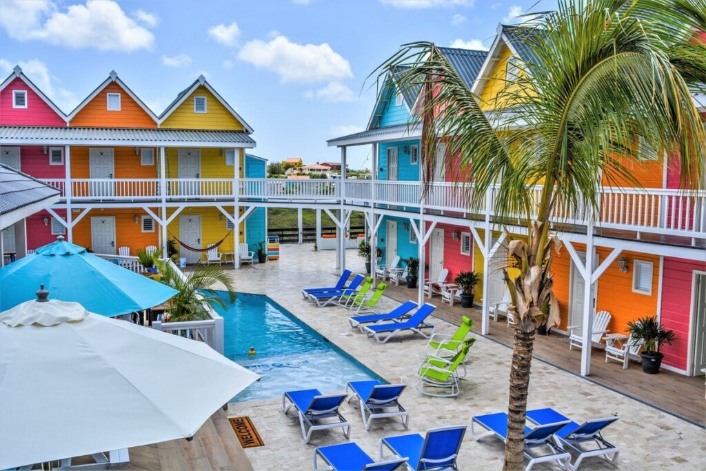 Cour arrière colorée avec piscine et chaises longues de l'hébergement choisi pour le voyage organisé sur l'île de Curaçao entre femmes #curacao #antilles #caraibes #voyageentrefemmes #voyage #voyagedegroupe #voyageorganise