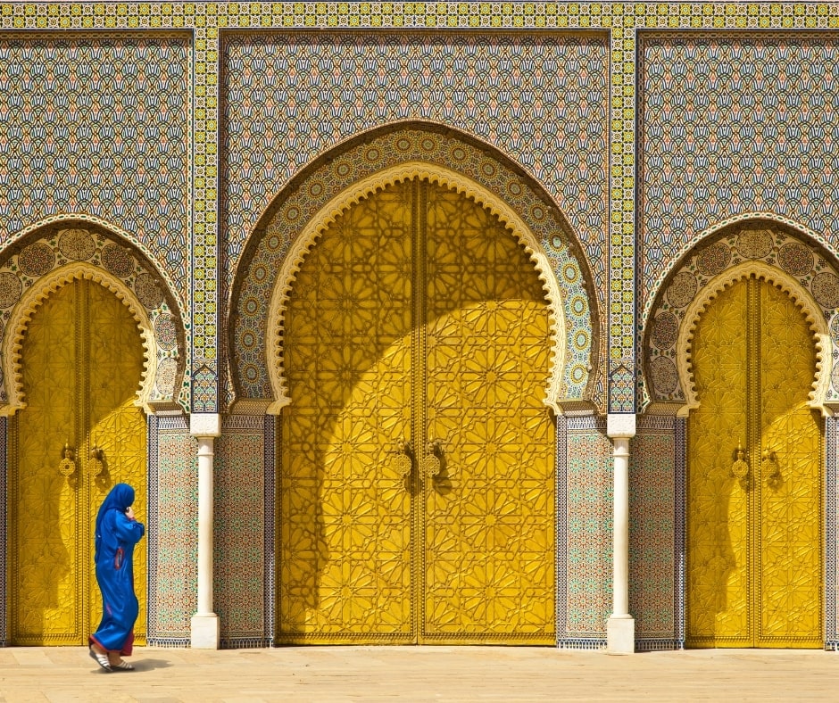 Portes de couleurs jaunes avec une femme en bleu qui marche devant, à Fès voyage organisé au Maroc entre femmes #maroc #afriquedunord #voyage #voyageorganise #voyageentrefemmes